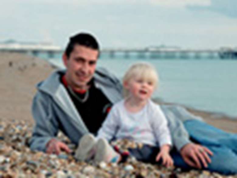 Child on a beach with father. Credit: Alex Deverill