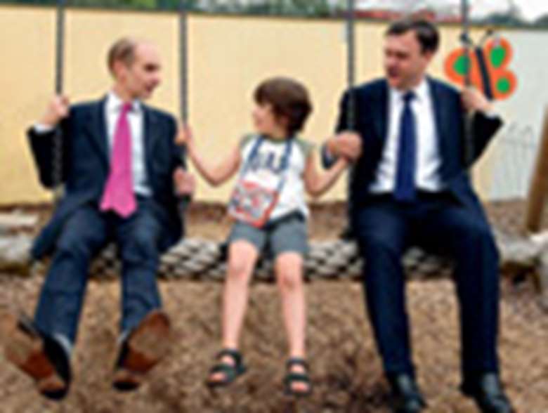 Ministers Ed Balls and Andrew Adonis with a child on a swing. Credit: Alex Deverill