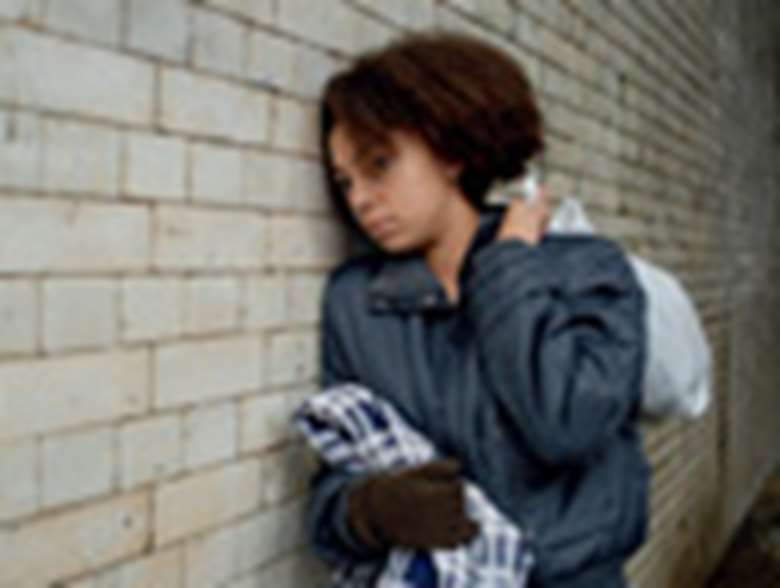 Girl leaning against wall with blanket. Posed by model. Credit: The Children's Society